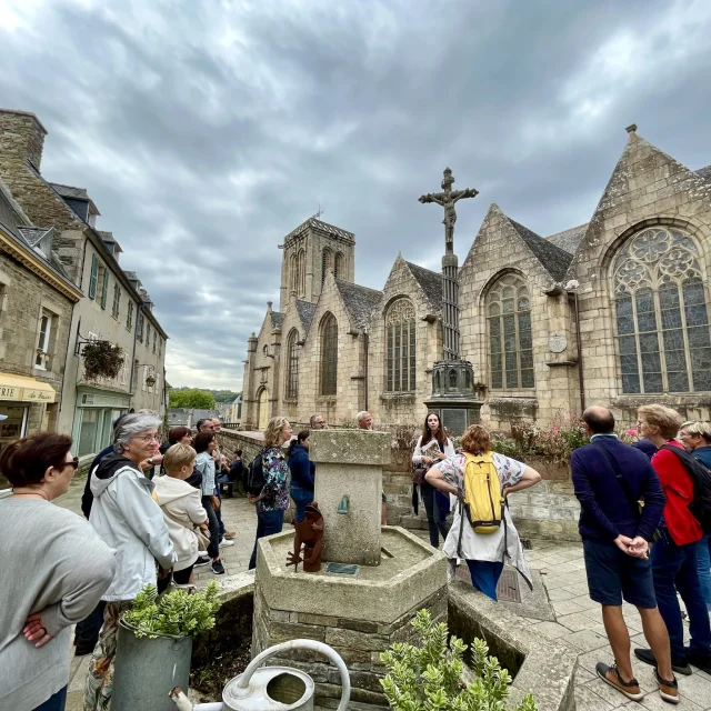 Ella, guide conférencier accompagne un groupe devant l'église Saint-Jean-du-Baly pour une visite guidée de Lannion