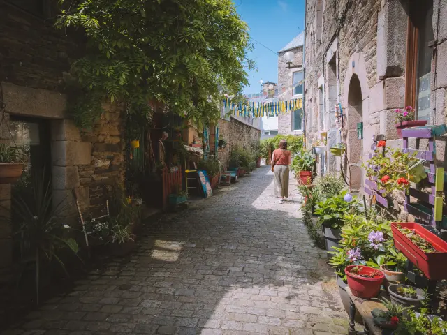 Un femme se promène dans une venelle fleurie de Lannion