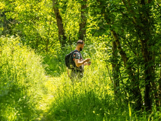 Un homme est sur un sentier forestier en bord de rivière