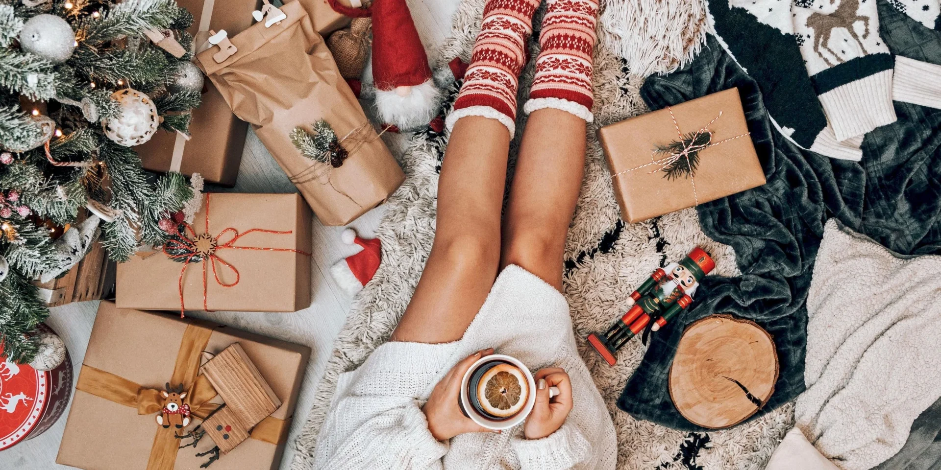 une femme assisse avec des cadeaux de Noël autour d'elle