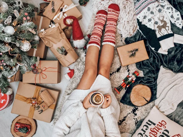 une femme assisse avec des cadeaux de Noël autour d'elle