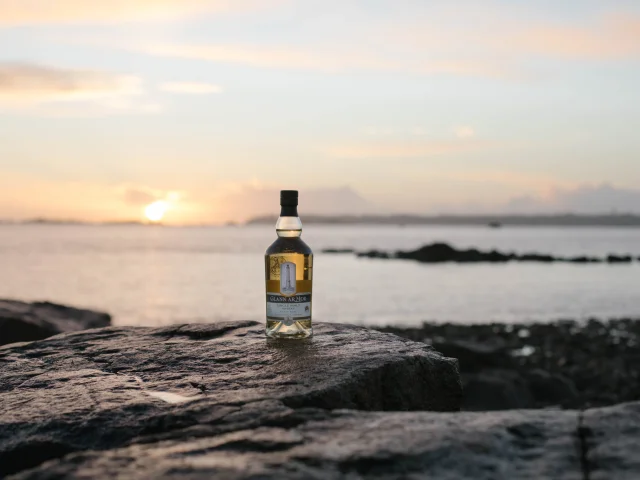 Une bouteille de Celtic Whisky sur un rocher au soleil couchant