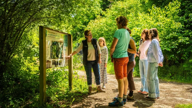 Balade ludique : le diable est à Kernansquillec : le groupe est devant le panneau de l'entrée du site écoutant les premiers commentaires de la guide
