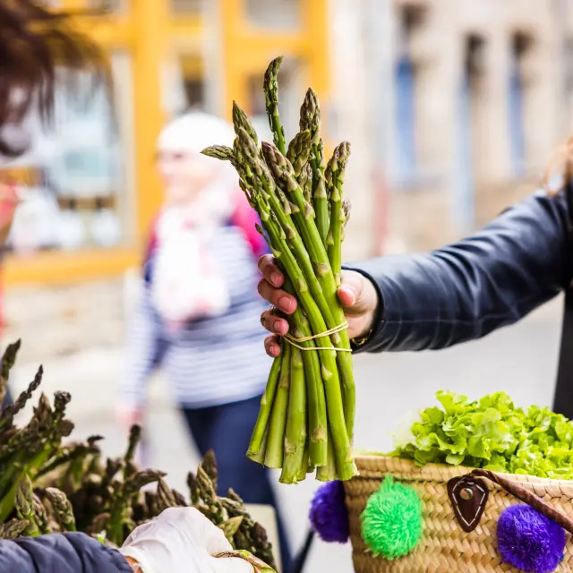 Une dame tenant une botte d'asperge sur le marché de Tréguier