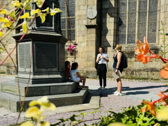 Balade Ludique de Lannion. La famille écoute les commentaires de la guide face à l'église Saint-Jean du Baly