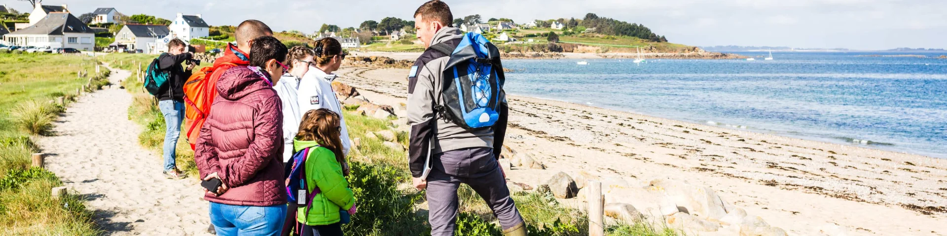 Un groupe de personnes écoute les informations données par un guide le long d'une plage.