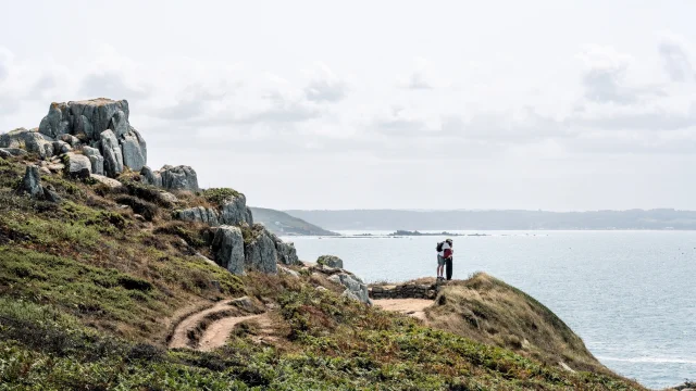 Un couple observe la mer lors d'une randonnée sur le GR34 à Trébeurden