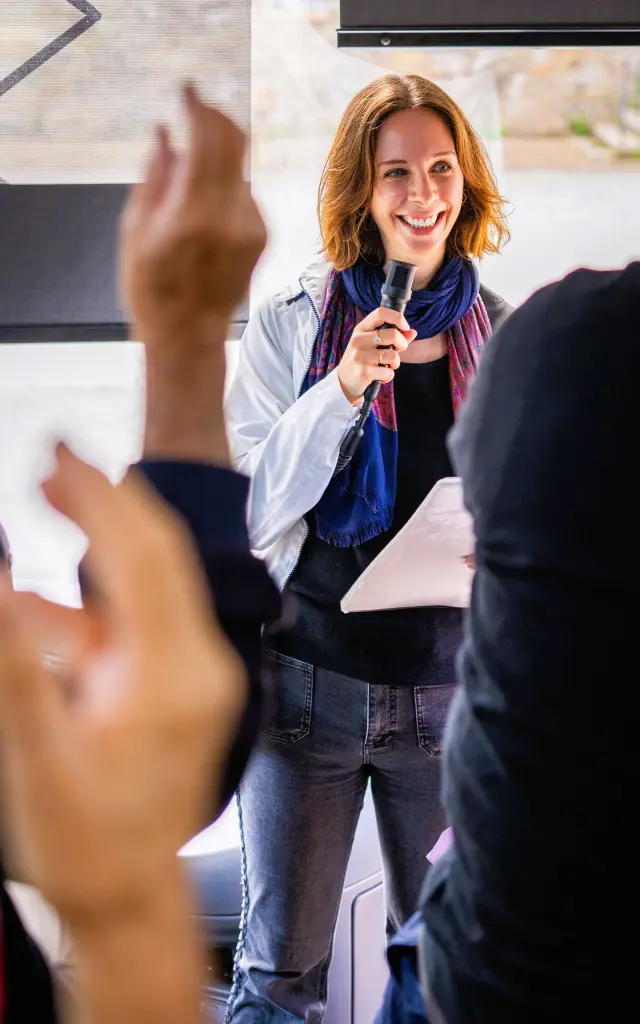 Une guide-conférencière au micro devant un groupe de touristes durant une visite guidée