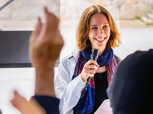 Une guide-conférencière au micro devant un groupe de touristes durant une visite guidée