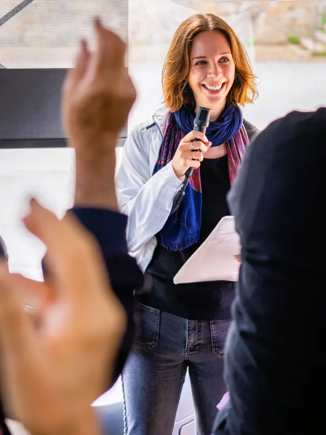 Une guide-conférencière au micro devant un groupe de touristes durant une visite guidée