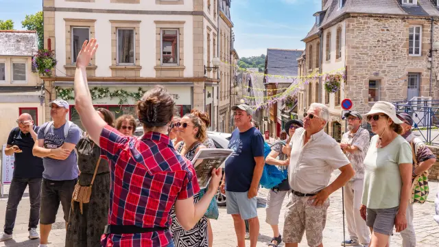 Une guide montre un monument de Lannion à des touristes dans Lannion