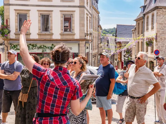 Une guide montre un monument de Lannion à des touristes dans Lannion