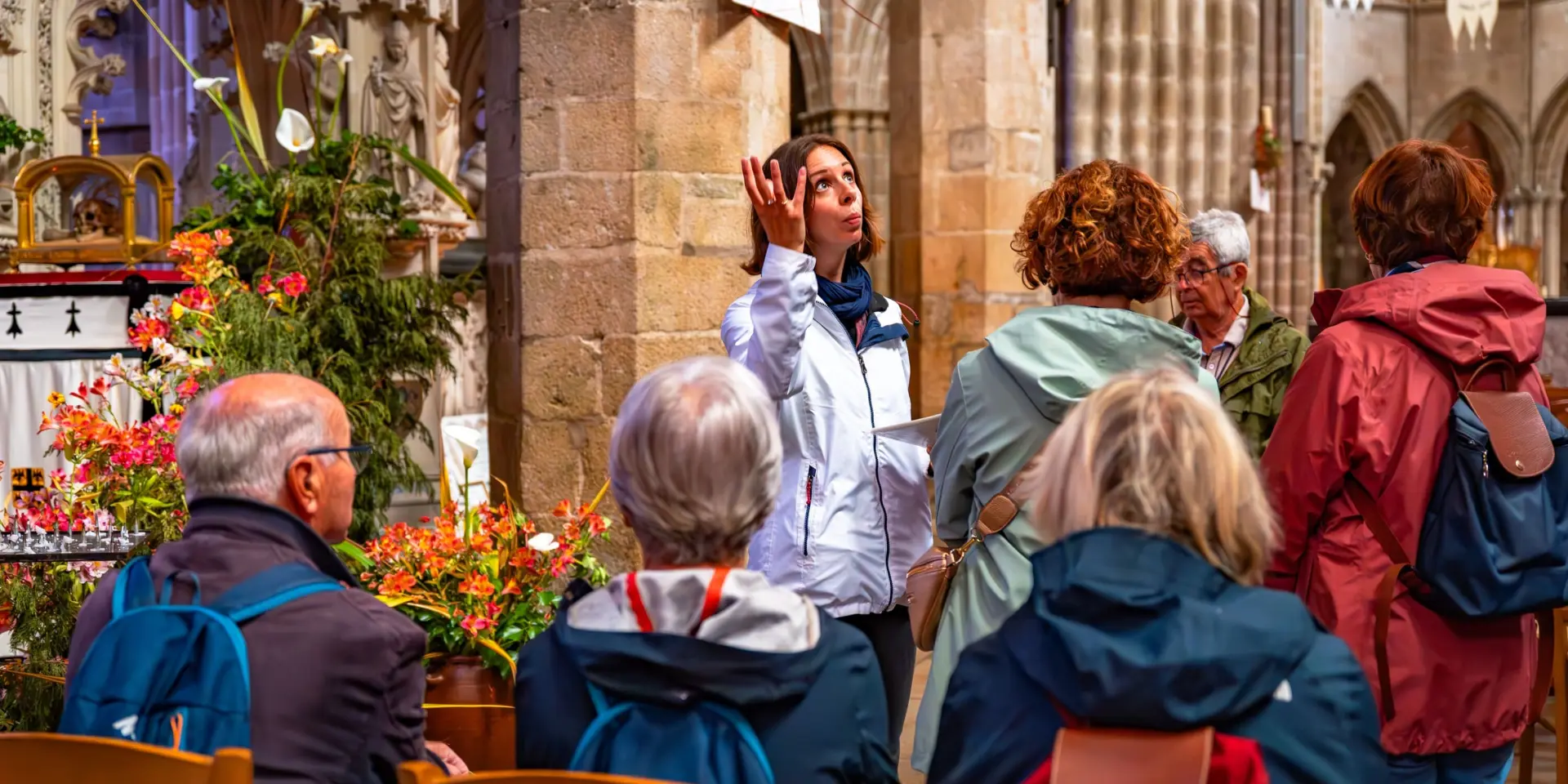 Une guide montre la nef du Elise à un groupe de touriste en visite guidée.