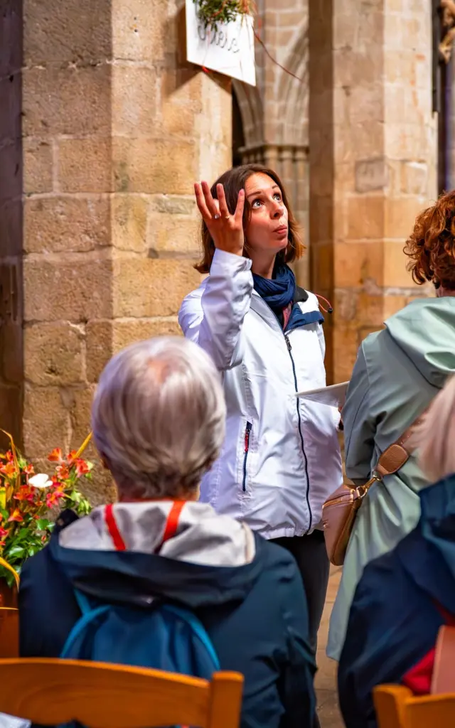 Une guide montre la nef du Elise à un groupe de touriste en visite guidée.