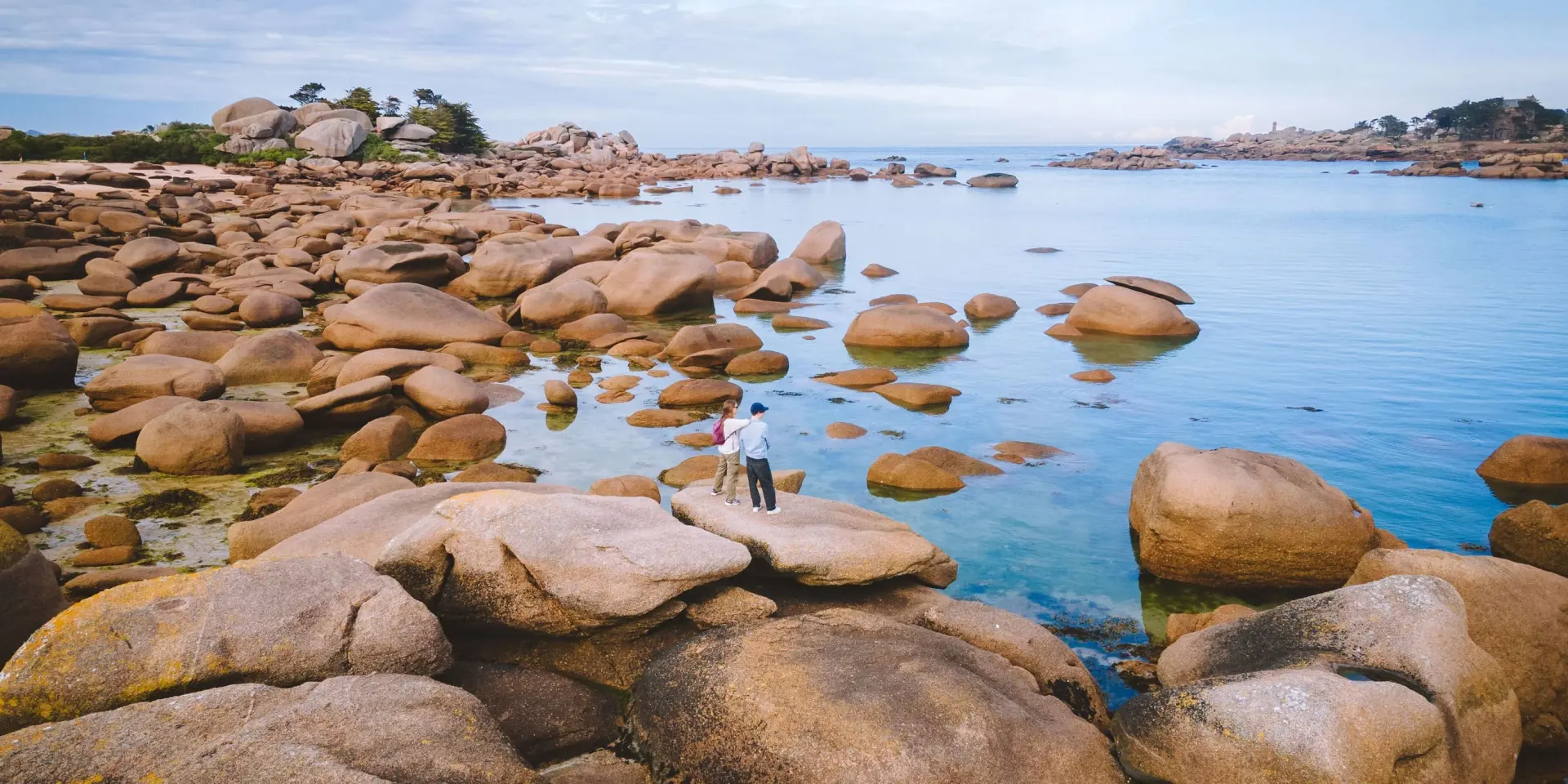 Sur la Presqu'île Renote à Trégastel, debout sur un rocher, un couple contemple la mer.