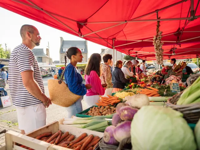 Des personnes font la queue devant l'étale d'un maraîcher sur le marché de Trébeurden