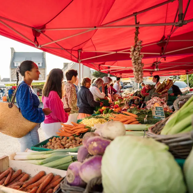 Des personnes font la queue devant l'étale d'un maraîcher sur le marché de Trébeurden