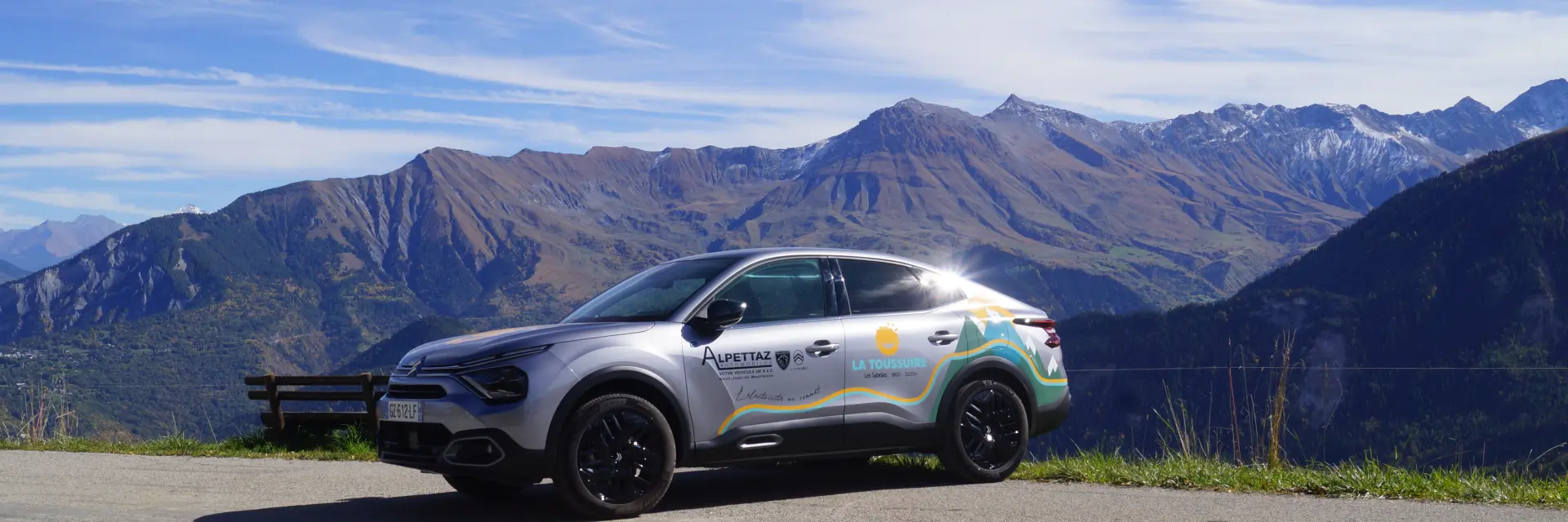 Véhicule électrique gris garé sur un chemin de terre en montagne