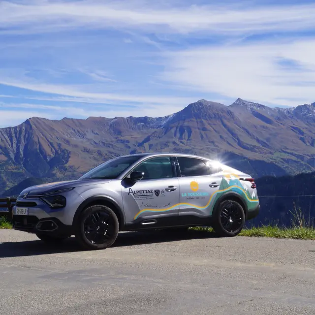 Véhicule électrique gris garé sur un chemin de terre en montagne