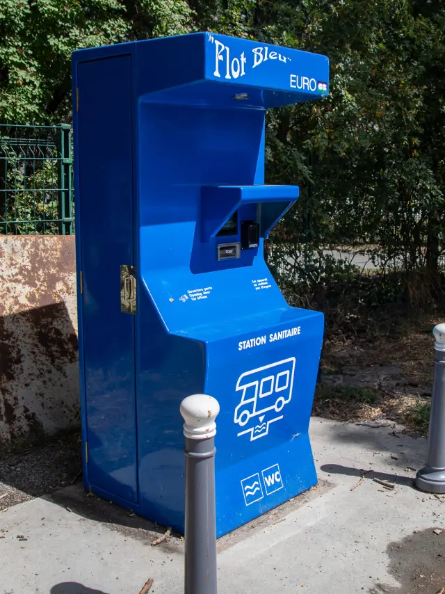 borne bleu et blanc avec logo Flot Bleu Pro, installé en extérieur près d’un chemin de terre