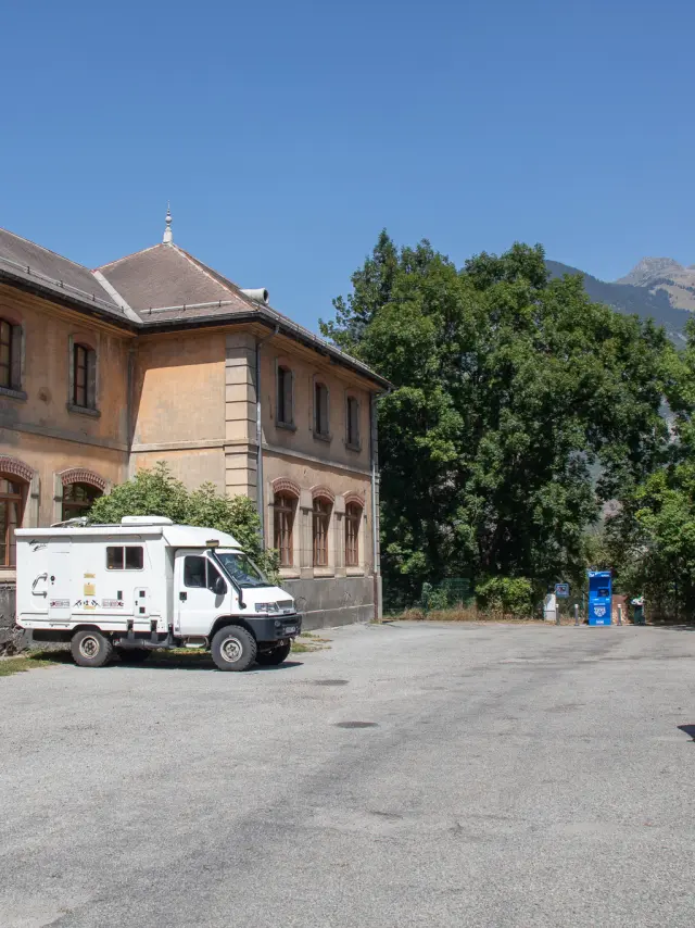 Deux campings cars blancs stationnés devant une résidence avec des arbres et des bâtiments en arrière-plan