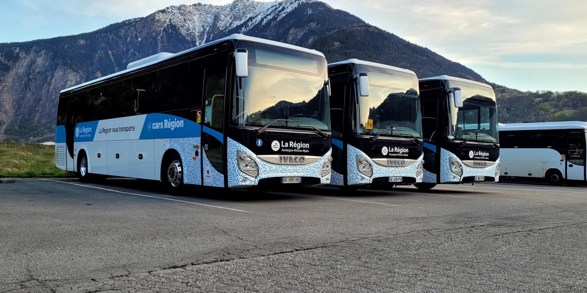 Bus de tourisme blanc et bleu avec logo Cityliner garé sur un parking en montagne
