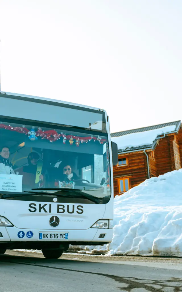 Bus blanc marqué 'Ski Bus' transportant des skieurs sur la station de La Toussuire