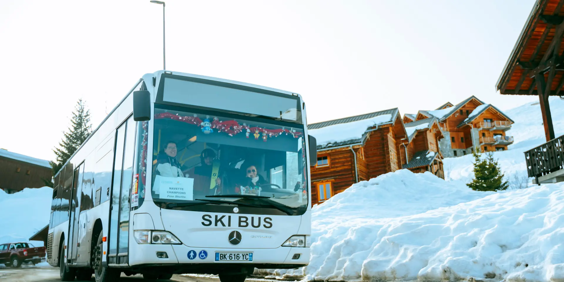 Bus blanc marqué 'Ski Bus' transportant des skieurs sur la station de La Toussuire