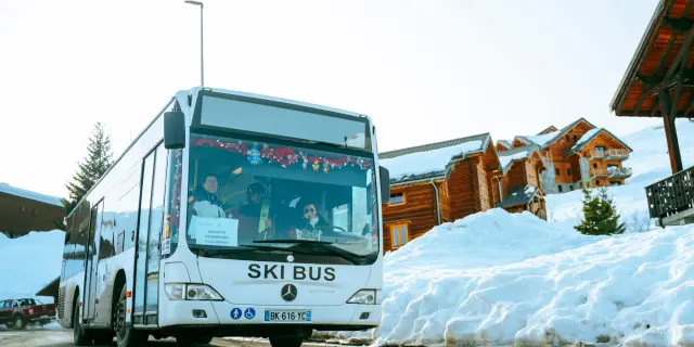 Bus blanc marqué 'Ski Bus' transportant des skieurs sur la station de La Toussuire