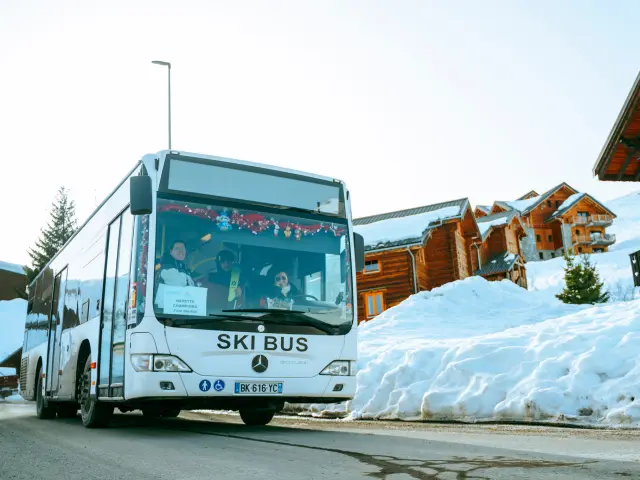 Bus blanc marqué 'Ski Bus' transportant des skieurs sur la station de La Toussuire