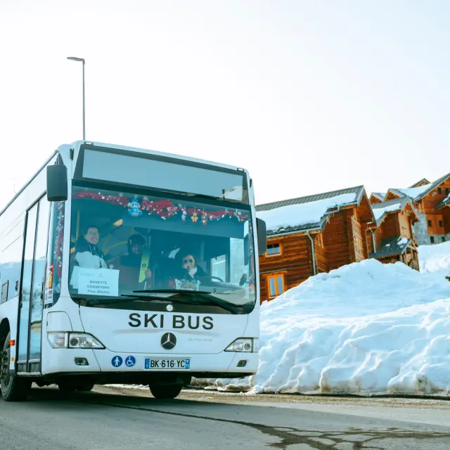 Bus blanc marqué 'Ski Bus' transportant des skieurs sur la station de La Toussuire