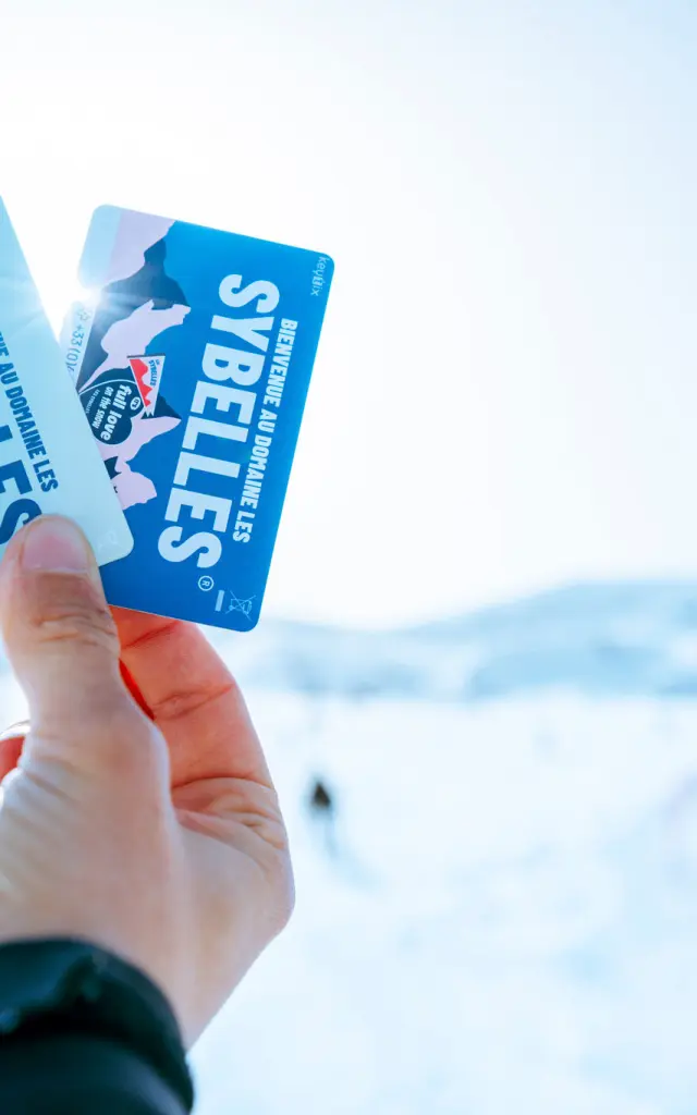 Deux forfaits de ski tenus dans une main avec un fond flou