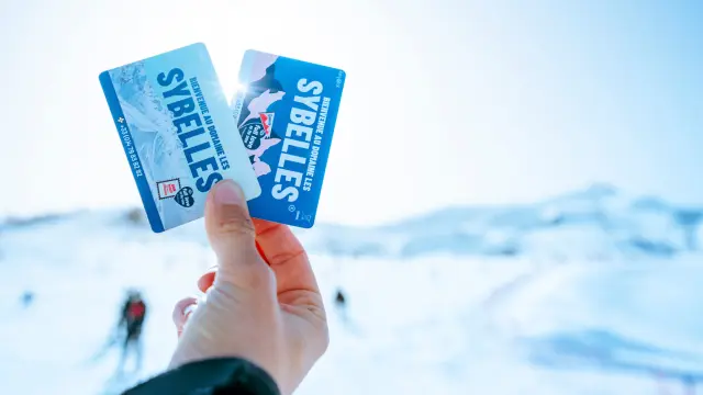 Deux forfaits de ski tenus dans une main avec un fond flou