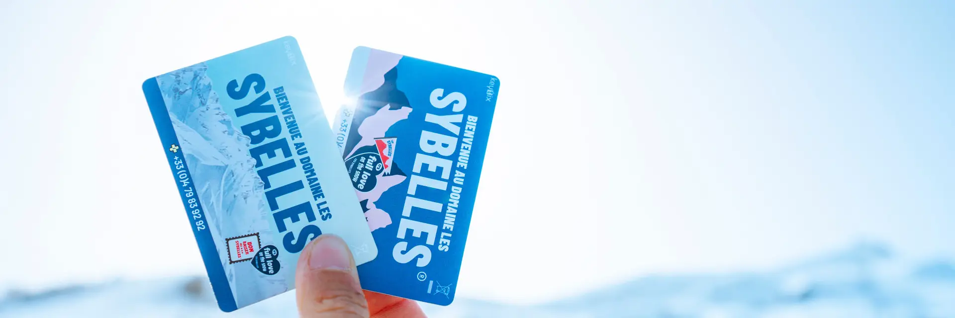 Deux forfaits de ski tenus dans une main avec un fond flou
