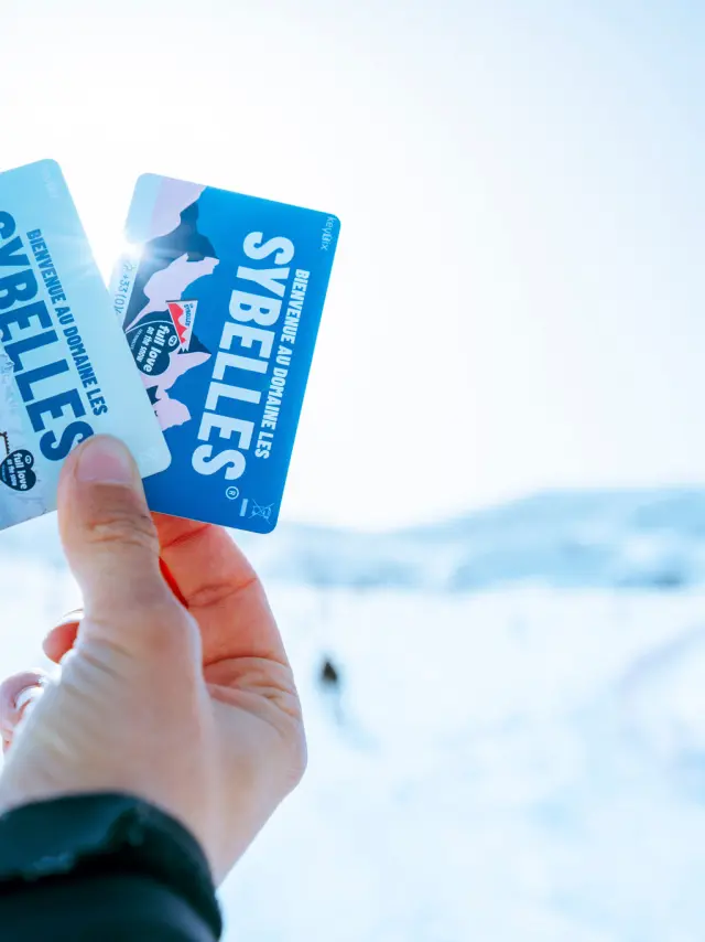Deux forfaits de ski tenus dans une main avec un fond flou