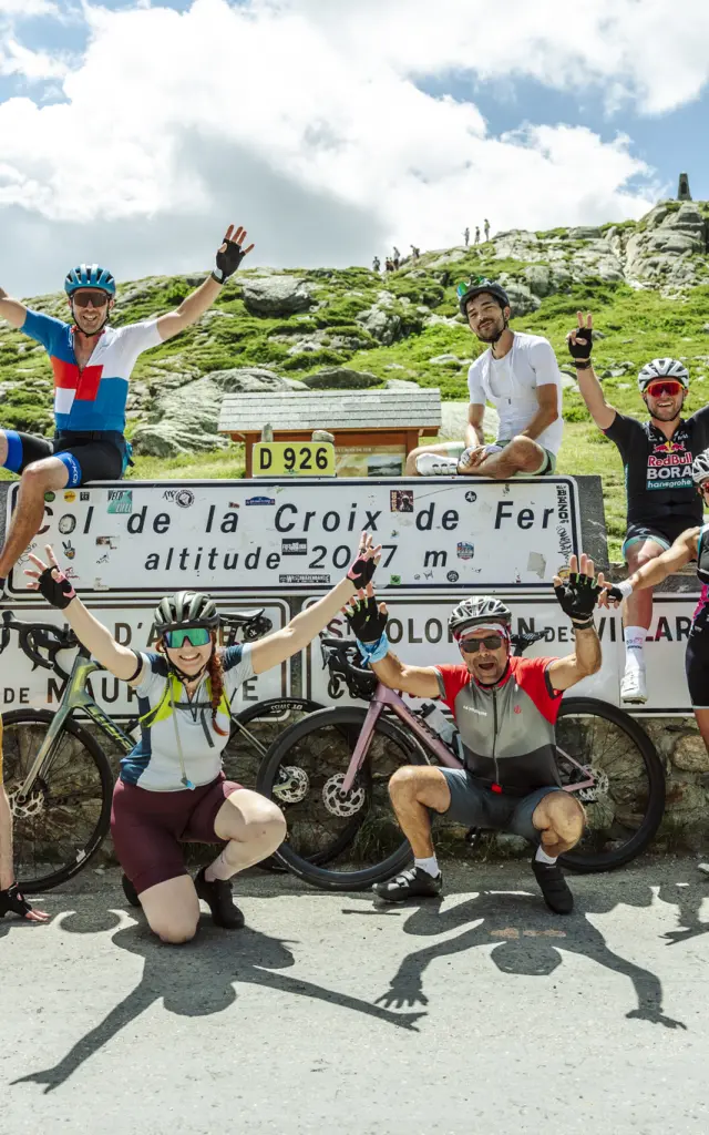 Cyclistes en compétition sur une route de montagne à La Croix de Fer, avec un panneau indiquant l'altitude de 2047 mètres