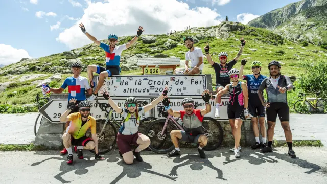 Cyclistes en compétition sur une route de montagne à La Croix de Fer, avec un panneau indiquant l'altitude de 2047 mètres