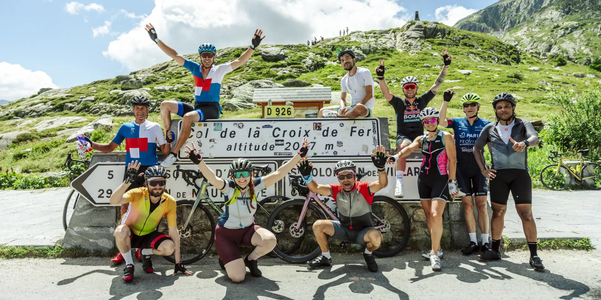 Cyclistes en compétition sur une route de montagne à La Croix de Fer, avec un panneau indiquant l'altitude de 2047 mètres