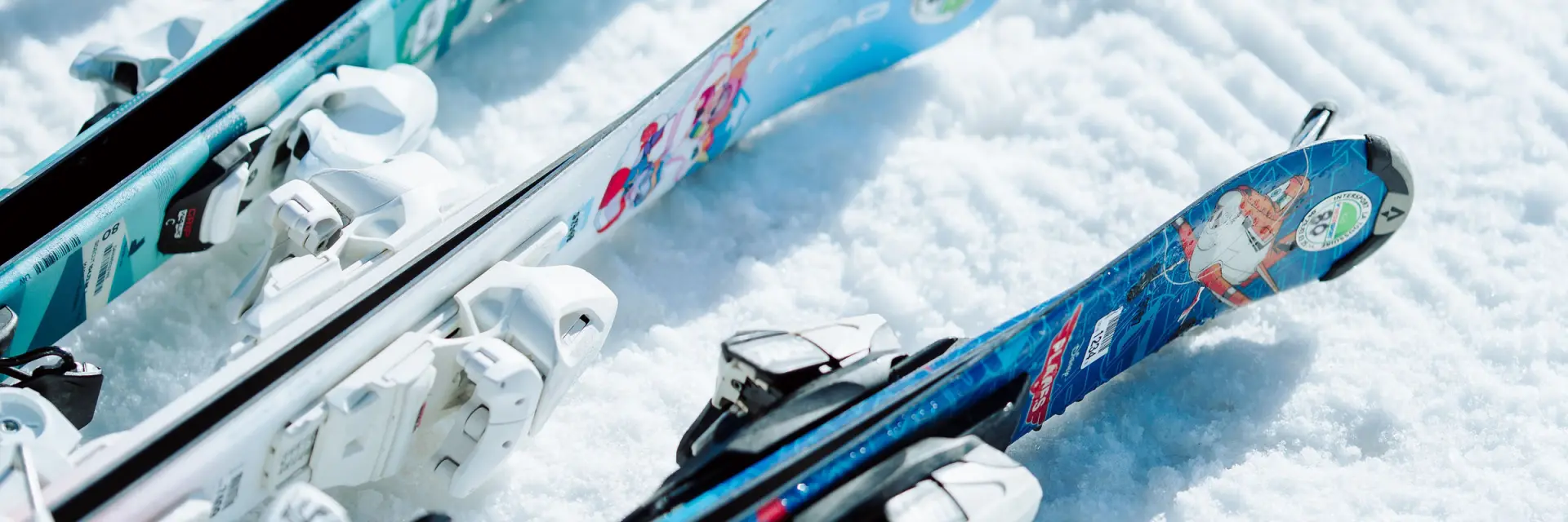 Des paires de ski enfants posées dans la neige