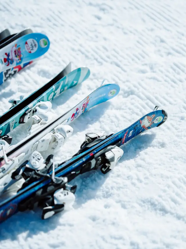 Des paires de ski enfants posées dans la neige