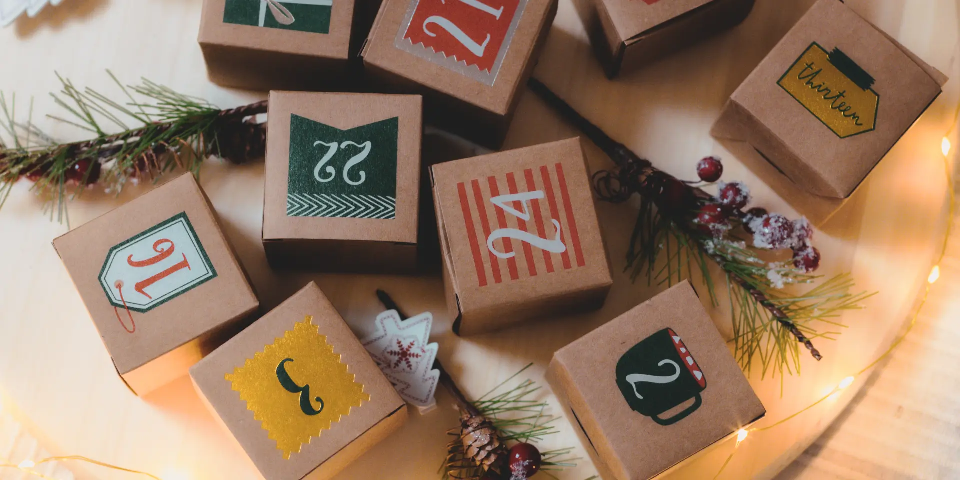 Craft advent calendar box with numbers, inscriptions and Christmas decoration with a burning garland on a wooden tray lie on the bed in the bedroom, close-up top view.