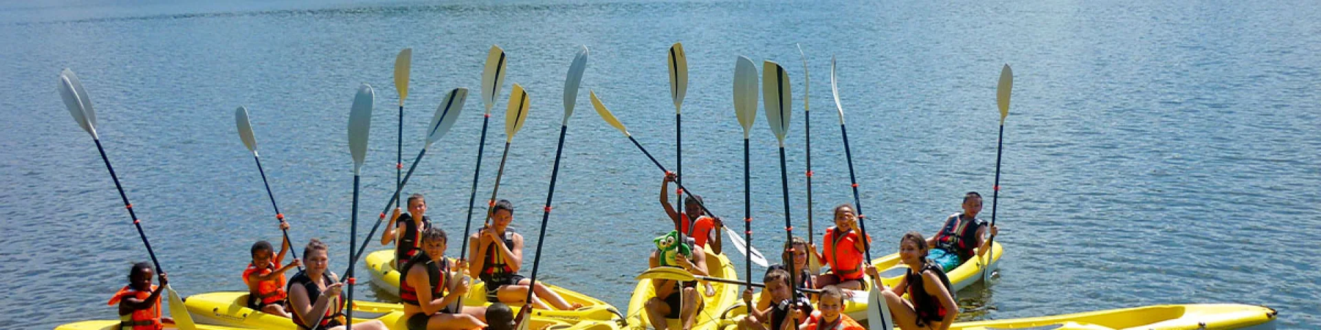 Groupe d’enfants et ados en canoë sur le lac du Tolerme lors d’une animation estivale au Village Club & Spa Terrou