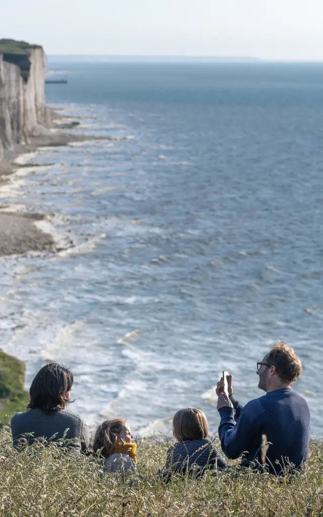 Une famille profitant du panorama sur le sentier du littoral pour faire une pause dans les champs