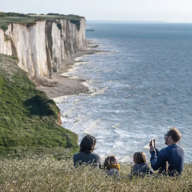 Une famille profitant du panorama sur le sentier du littoral pour faire une pause dans les champs