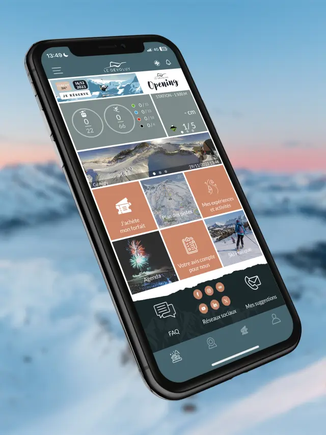 Smartphone displaying the Dévoluy mobile app with resort information and snowy mountains in the background.