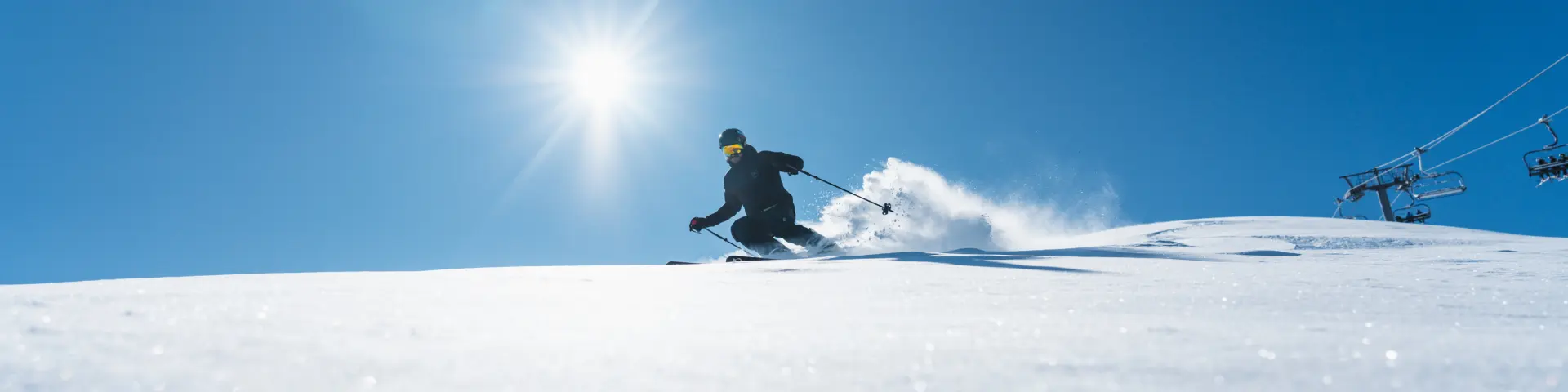 Skiër die een besneeuwde piste afdaalt onder een stralende zon in het alpineskigebied van Le Dévoluy.