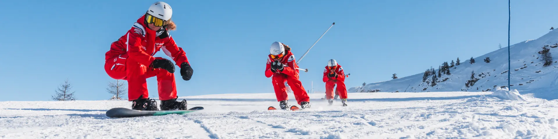 Moniteurs de l’ESF en tenue rouge réalisant une démonstration de ski sur une piste enneigée au Dévoluy.