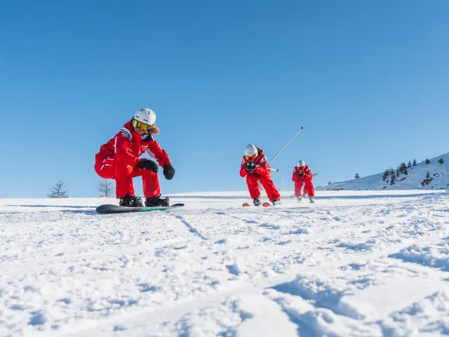 Moniteurs de l’ESF en tenue rouge réalisant une démonstration de ski sur une piste enneigée au Dévoluy.