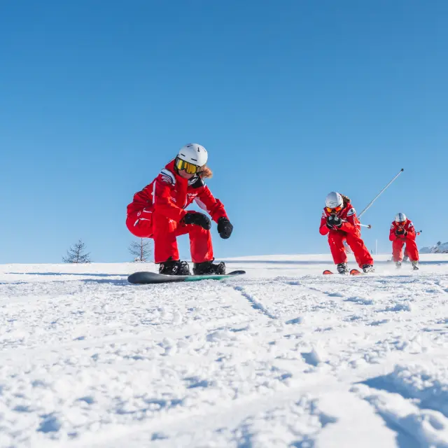 ESF-skileraren in rode outfit tijdens een skidemonstatie op een besneeuwde piste in Le Dévoluy.