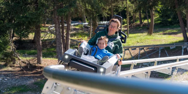 Une femme et son fils dévalent la pente sur la luge 4 saisons de Superdévoluy.